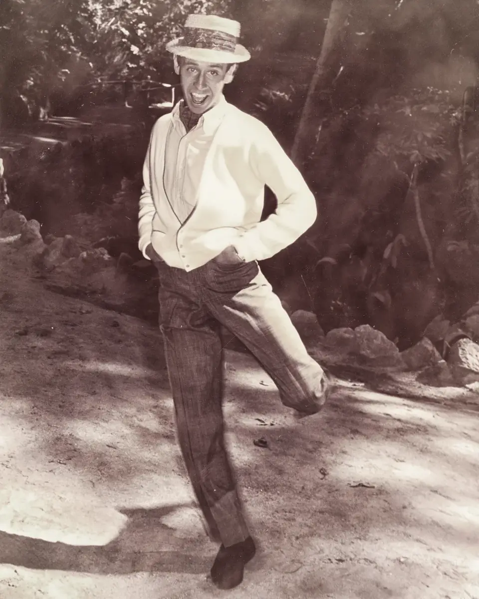 Young Dean in a straw hat, mid-step on a dirt path