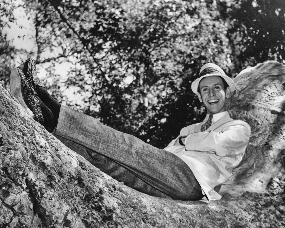 Young Dean in a straw hat, stretched out on a large tree branch